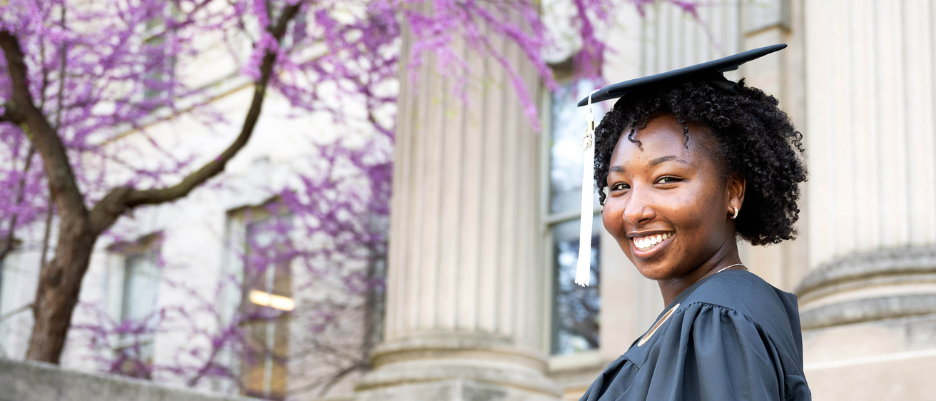 Virginia Muturi in cap and gown on the Pentacrest