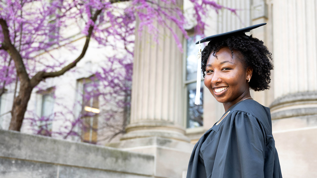 Virginia Muturi in cap and gown on the Pentacrest