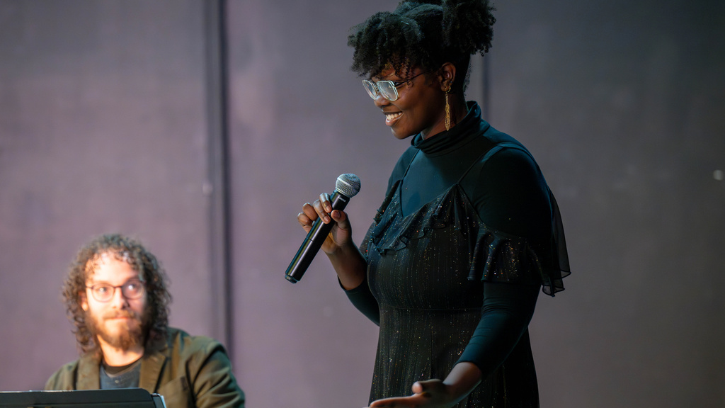Cianon Jones smiling while holding a microphone at her Arts Share commission in Muscatine, IA